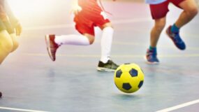 Three children play soccer outside.